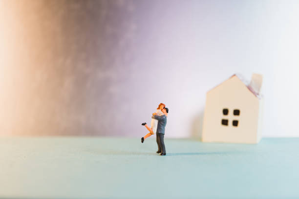 istock Miniature people, lovers standing on mini house 1477185471