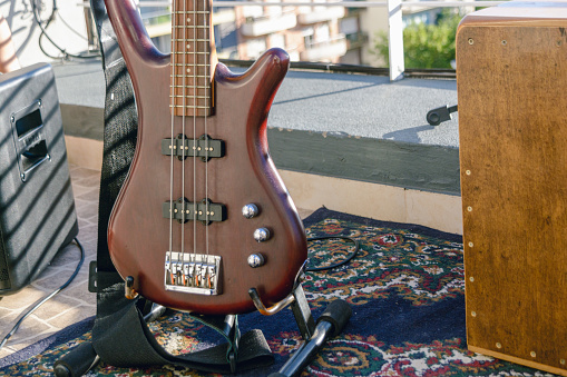 closeup of body of red burgundy bass guitar perched on stand, live music set, music concept, copy space.