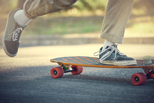 A close-up of a young skateboarders feet boy pushing a skateboard in the city park