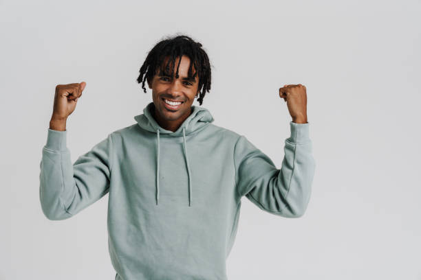 istock Excited young african man gesturing as winner while standing isolated 1477186181