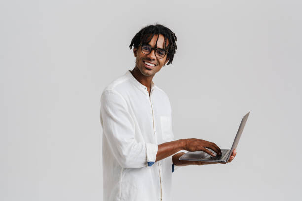 istock Black young man in eyeglasses smiling while working with laptop 1477188104