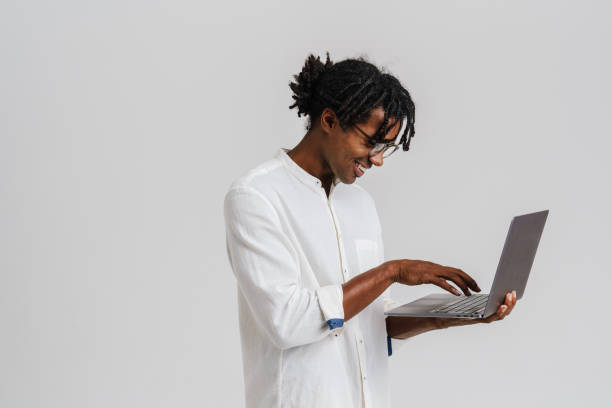 istock Black young man in eyeglasses smiling while working with laptop 1477188114