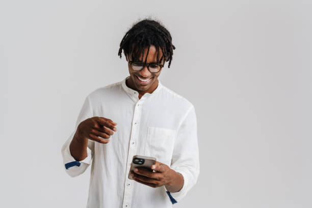 istock Black young man in eyeglasses smiling while using mobile phone 1477188139