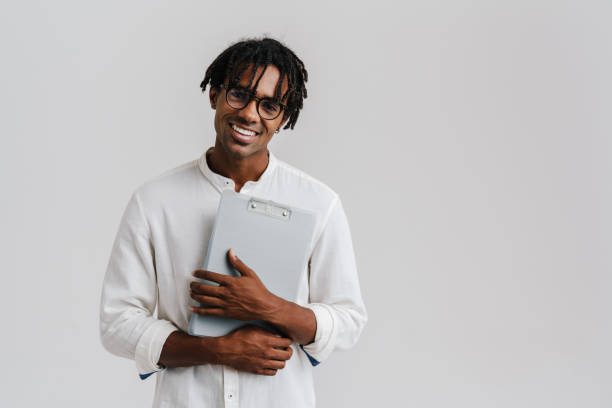 istock Black young man in eyeglasses smiling while posing with clipboard 1477188226