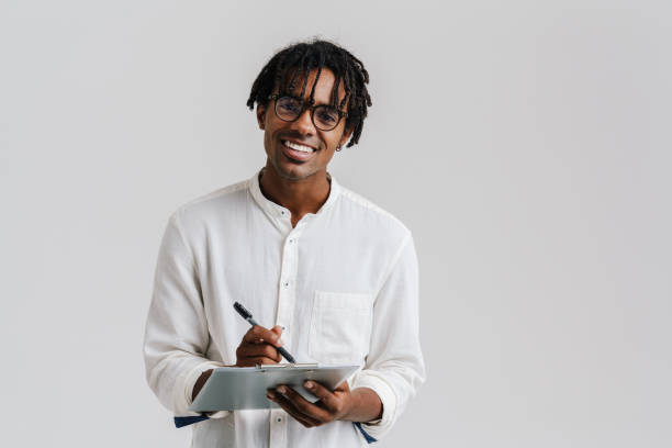 istock Smiling young man holding clipboard isolated over white background 1477188631