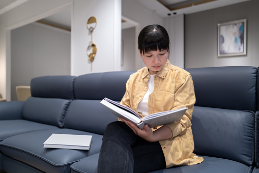 A woman sitting on the sofa reading a book