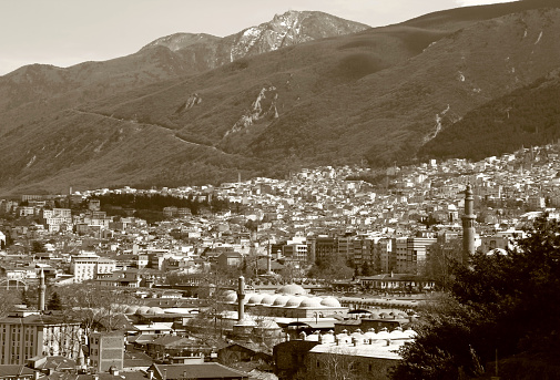 A panoramic view of the city of Bursa with many mosques, hans and Uludag mountain in the background with sepia effect
