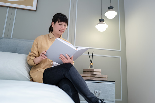 Woman sitting on bed reading book