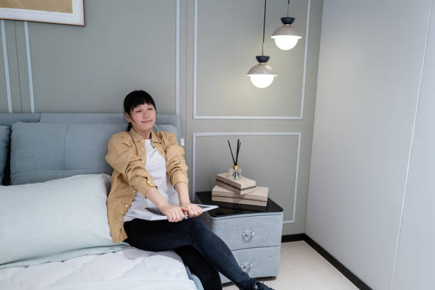 istock Woman sitting on bed reading book 1477189428