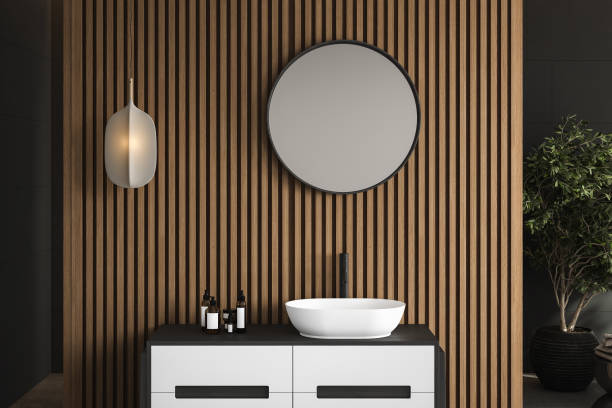 istock 3D rendering close up of a modern vanity unit in the bathroom with round mirror on white basin, white square tiles and wood wall. Morning Sunlight, Products display background, Mock up. 1477190025