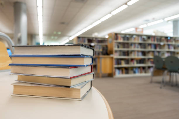 Stack of books on table at library stock photo