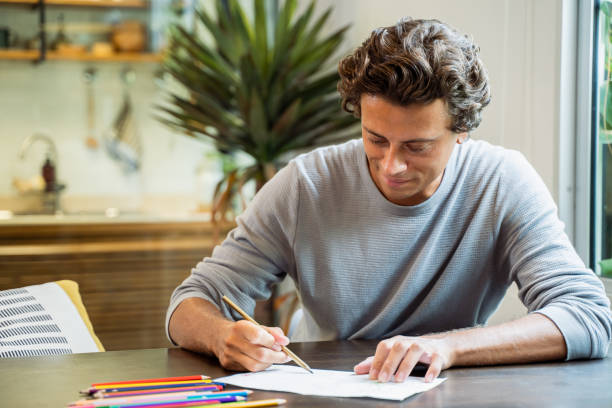 istock Young latin man designing using pencils and crayons for free designing ideas ideas in the comfort of home. 1477190847