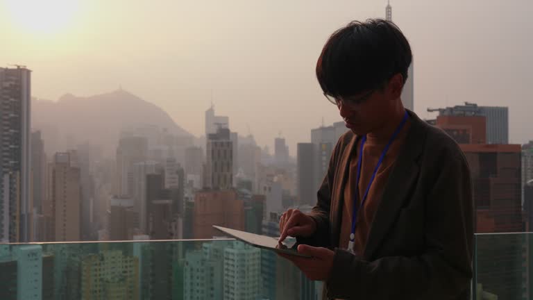 Businessman using tablet on roof top with sunset time