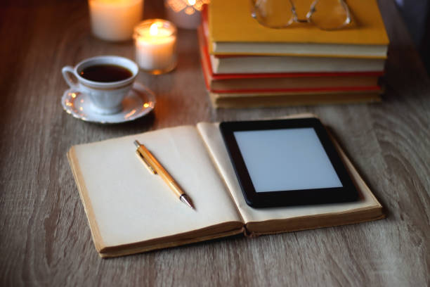 книги, стаканы, электронная читалка, ручка, чай, печенье и свечи - e reader digital tablet cafe reading стоковые фото и изображения