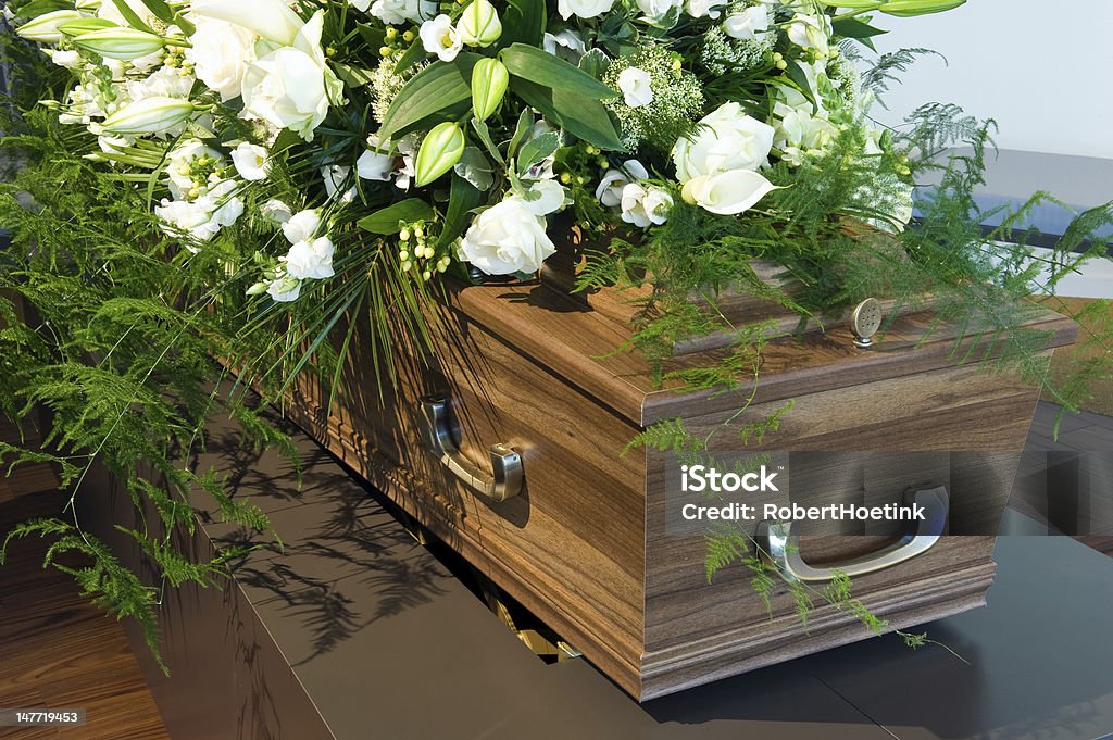Wooden Coffin in a morgue with white flowers A coffin in a morgue with a flower arrangement Coffin Stock Photo
