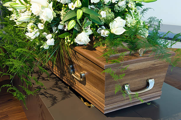Wooden Coffin in a morgue with white flowers A coffin in a morgue with a flower arrangement funeral parlor photos stock pictures, royalty-free photos & images