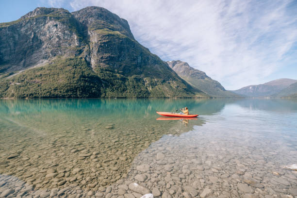 istock Man canoeing on a pristine lake through the mountains, the raft floats on the water surface, reflection 1477194613