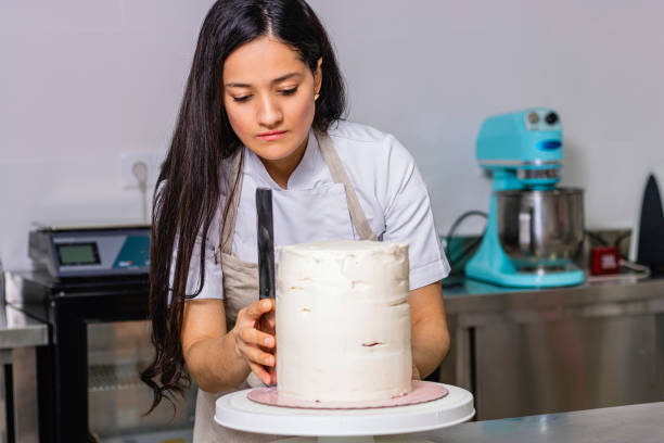 istock Colombian Pastry Chef. Chef working on a multi-tiered cake. 1477195086