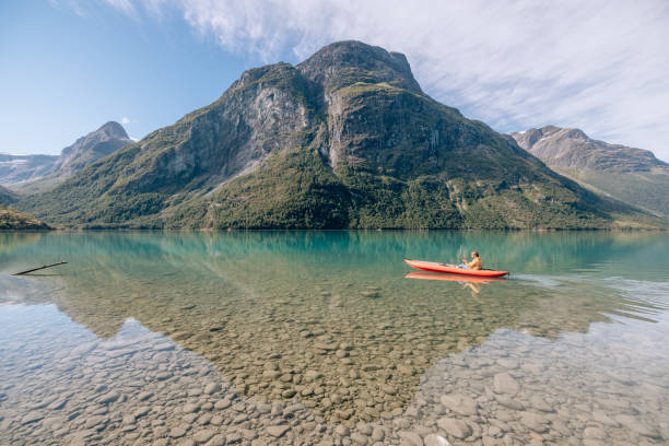 istock Man canoeing on a pristine lake through the mountains, the raft floats on the water surface, reflection 1477195514
