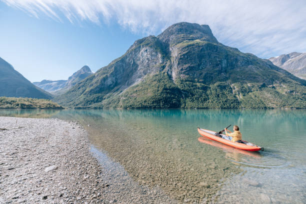 istock Man canoeing on a pristine lake through the mountains, the raft floats on the water surface, reflection 1477196259