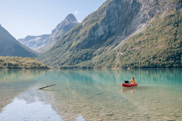 istock Man canoeing on a pristine lake through the mountains, the raft floats on the water surface, reflection 1477196372