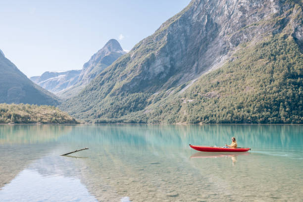istock Man canoeing on a pristine lake through the mountains, the raft floats on the water surface, reflection 1477196477