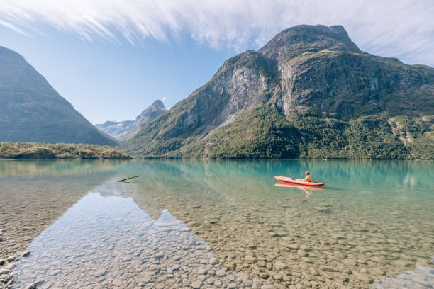 istock Man canoeing on a pristine lake through the mountains, the raft floats on the water surface, reflection 1477196496