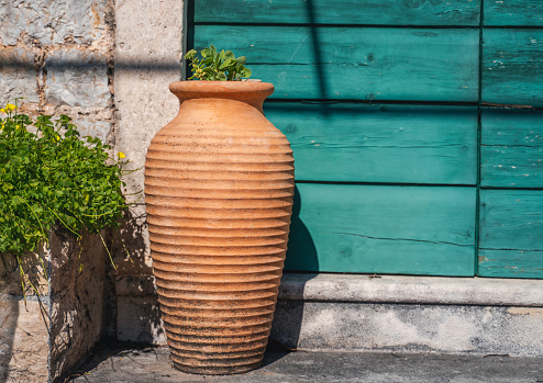 Clay terracotta pot amphora standing against the wall of a medieval house in a mediterranean resort