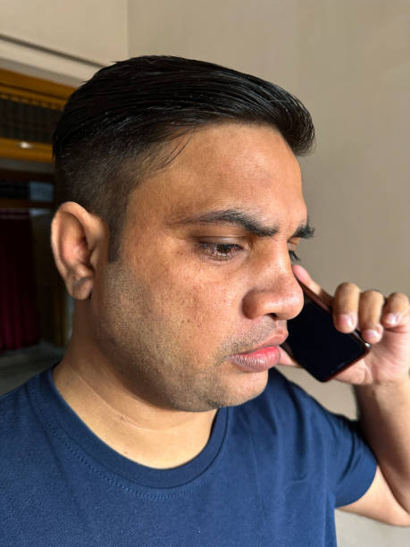 istock Full frame image of Indian man using mobile phone speaking indoors, communication using Smart phone to speak and listen, domestic room background, focus on foreground 1477198697