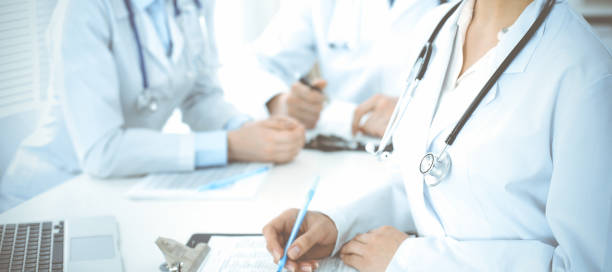 istock Group of unknown doctors discussing problems to stop coronavirus pandemic while sitting at meeting in clinic, close-up . Medicine concept 1477198749