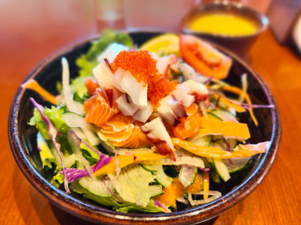 Healthy Salmon Sashimi Salad Close-up shot of healthy salmon sashimi salad, with salad dressing on the side. seafood salad stock pictures, royalty-free photos & images