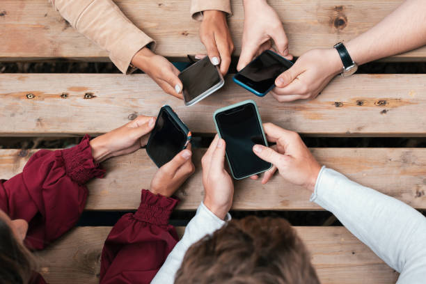 istock hands of young people in circle on table holding mobile phone - top view of hand using smartphone 1477201588