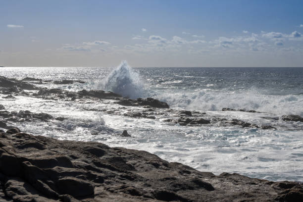 Beach of the Atlantic ocean with a rocky coast. Calm water in the winter. Blue sky with light clouds. Aquas Verdes, Playa del Valle, Fuerteventura, Canary Islands, Spain.