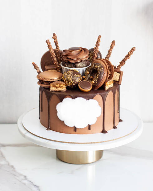 istock Gorgeous chocolate cake for birthday party lavishly decorated with cupcakes, donuts, candy, sweets with copy space for congratulations 1477202906