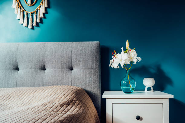 istock Cozy bedroom with turquoise blue walls and Boho home interior decor: macrame wall hanging decoration, white bedside table,vase with lilly flower, aroma lamp. Dark modern stylish room. Selective focus. 1477206485