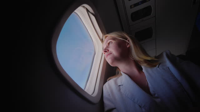 Young Caucasian woman traveling in an airplane, looking out the window