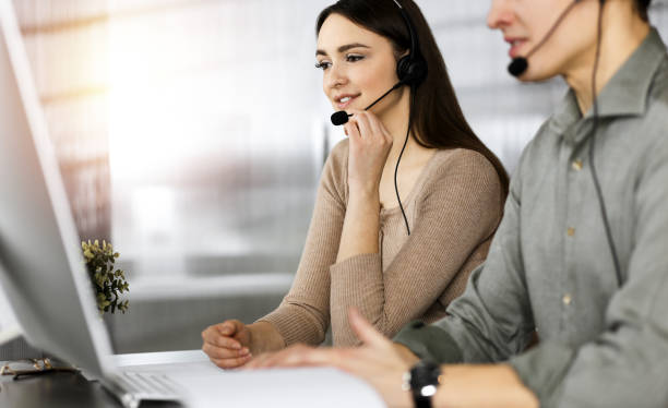 istock Call center operators at work. Two young people in headsets are talking to the clients, while sitting in sunny office 1477208087