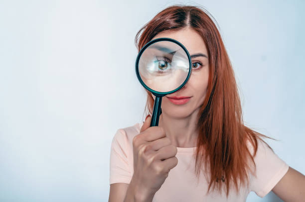 magnifying glass. a woman's face through a magnifying glass. long hair, big eyes. research, choice concept. - long hair red hair women men imagens e fotografias de stock