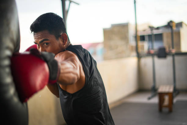 Portrait of young male boxing athlete Portrait of young male boxing athlete training in training room boxing stock pictures, royalty-free photos & images
