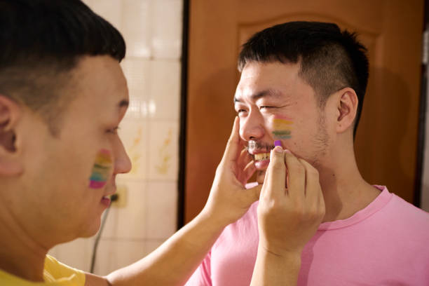 istock Homosexual couple draw rainbow color on their faces. 1477215248
