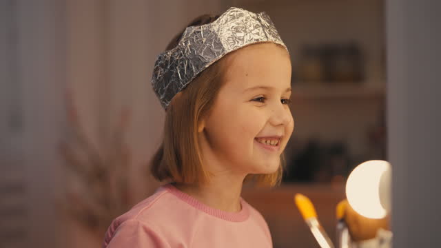 Smiling girl wearing foil crown and playing in front of mirror, little princess