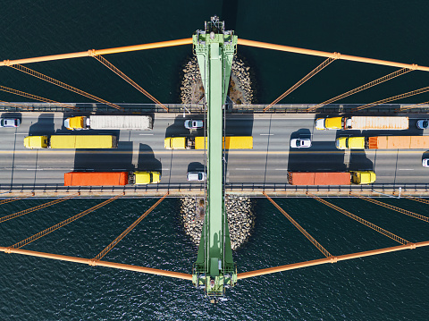 Aerial view of semi trucks crossing a suspension bridge.