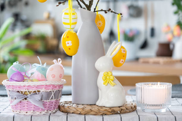 istock Easter decoration of colorful eggs in a basket and a rabbit on the kitchen table in a rustic style. Festive interior of a country house 1477217167
