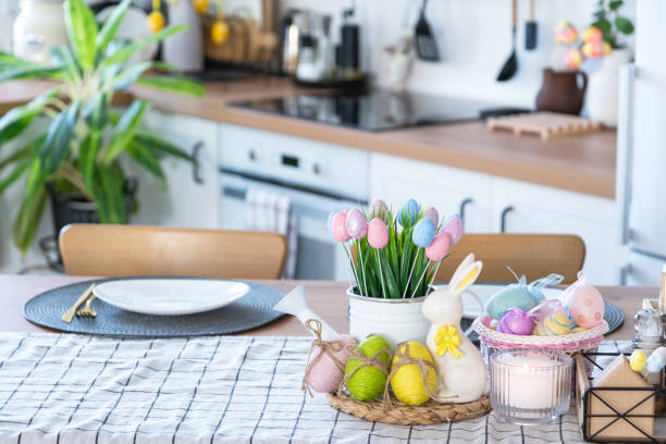 istock Easter decoration of colorful eggs in a basket and a rabbit on the kitchen table in a rustic style. Festive interior of a country house 1477217185