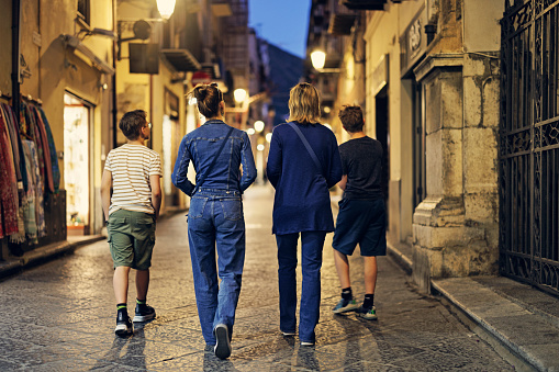 Family walking in beautiful narrow streets of Italian town of Cefalu. Warm spring evening in Italy, Sicily.
Mother and three teenagers are walking together in the street.
Canon R5