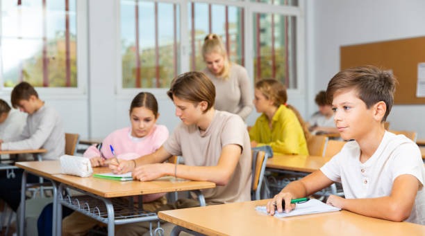 istock Teenagers sitting at desks in classroom during lesson 1477219626