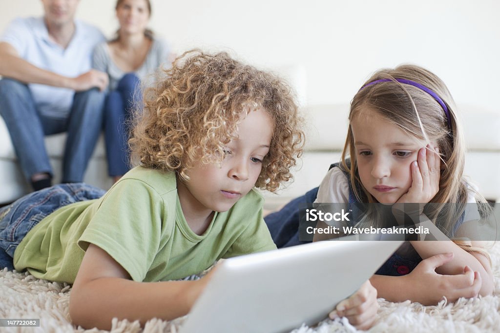 Les enfants à l'aide d'une tablette d'ordinateur alors que leurs heureux paren - Photo de Adulte libre de droits
