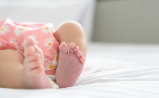 Cropped photo of a child's legs in pyjamas standing barefoot on the wooden herringbone flooring.