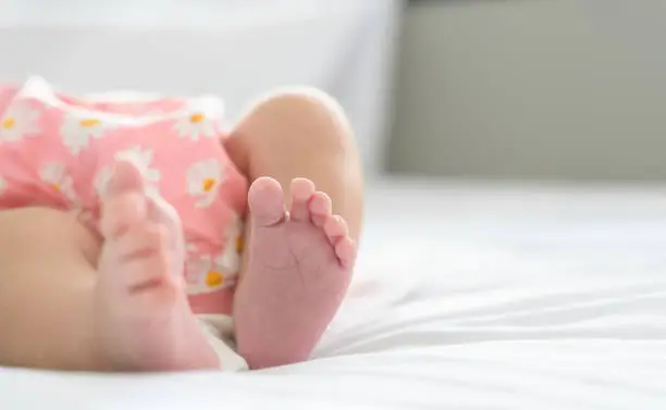 Photo of Cute little newborn baby feet on bed at home. Selective focus.