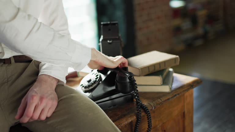 Unrecognisable man hangs up the phone handset after a conversation